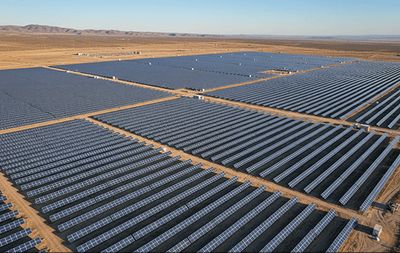 Large solar farm with rows of panels stretching across the landscape.